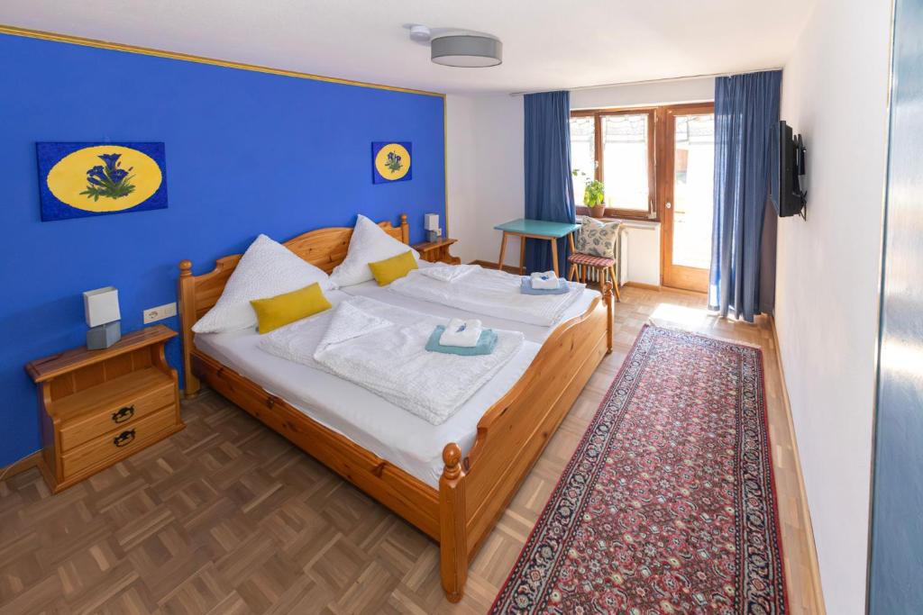 Un dormitorio con una cama con una pared azul. en Goldiger Hirsch B&B mit Kochmöglichkeiten, en Immenstadt im Allgäu