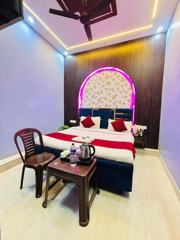 a bedroom with a large bed with a table and a chair at Vaidik Harmony Ayodhya in Ayodhya