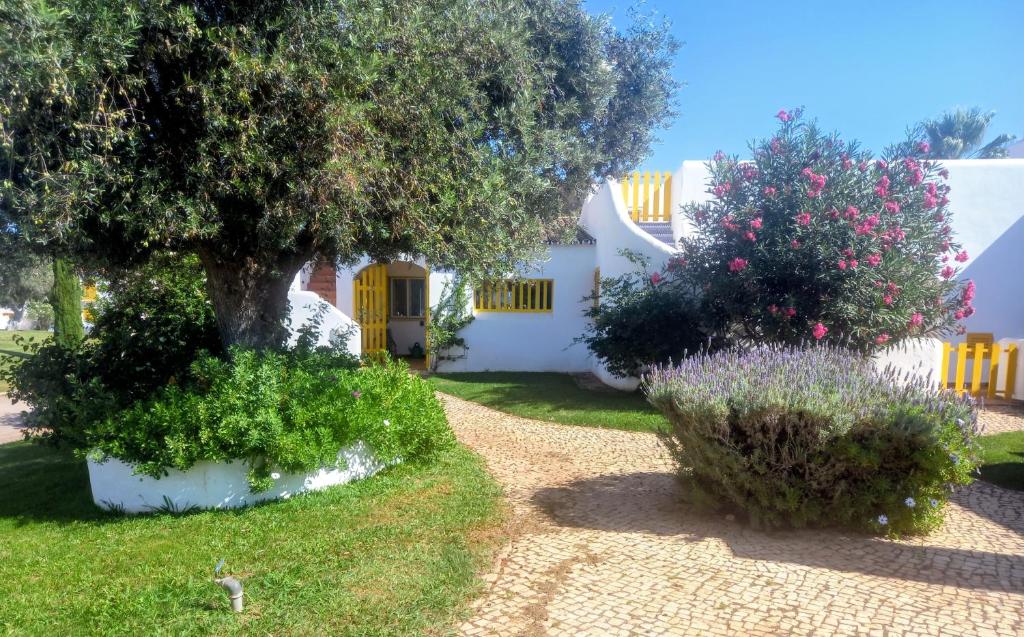 a garden with a tree and bushes in front of a house at Villa Blue - Aldeia do Golfe in Quarteira
