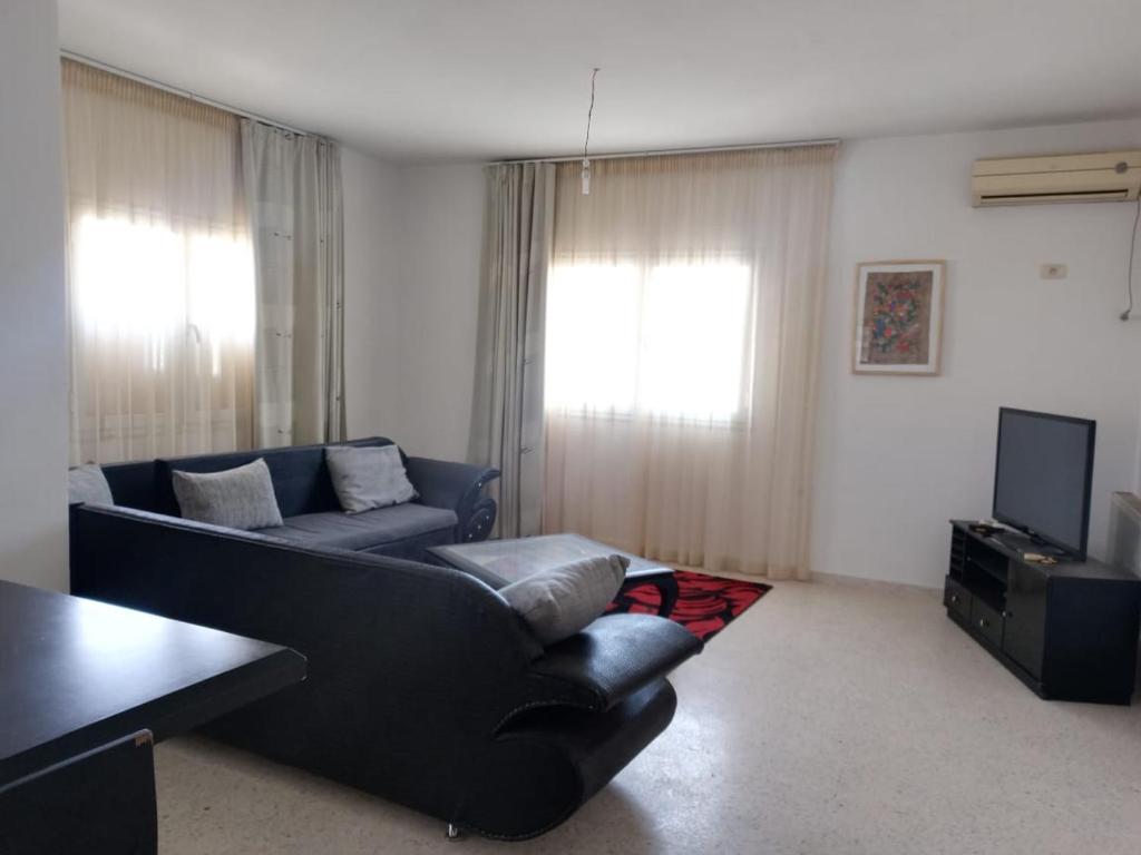 a living room with a couch and a tv at Dar selma in Port El Kantaoui