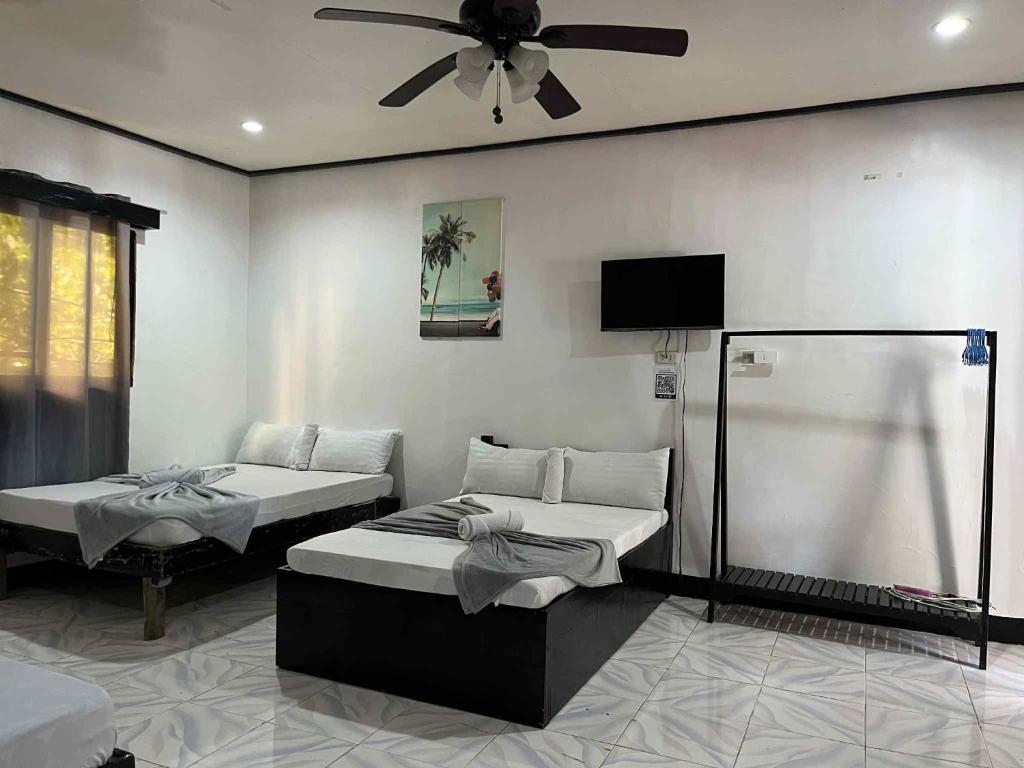 een slaapkamer met twee bedden en een plafondventilator bij Mia's Place in El Nido