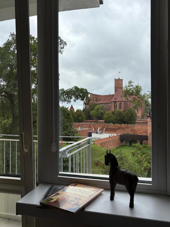 a dog statue sitting on a window sill with a book at Widok na Zamek in Malbork