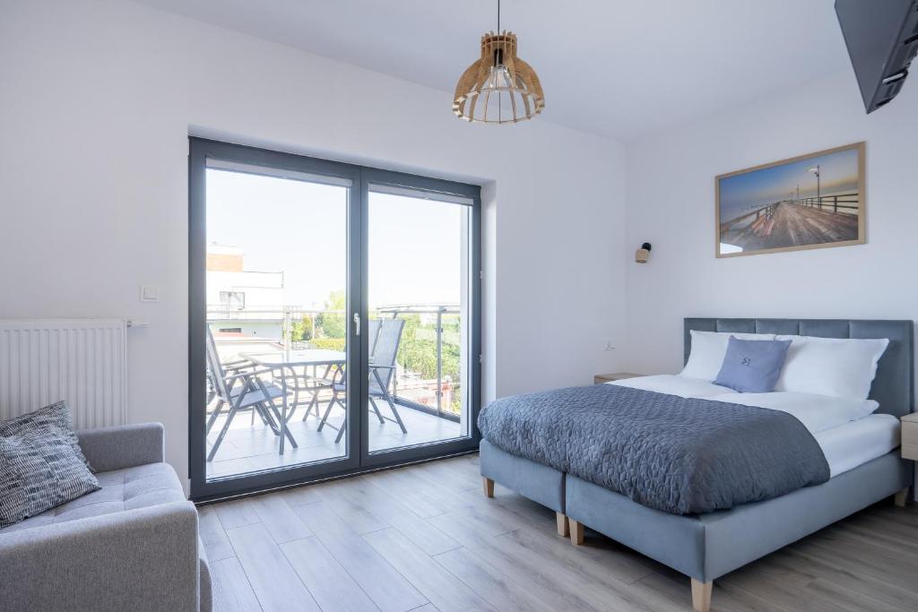 Un dormitorio con una cama y un sofá y un balcón. en S1 Apartamenty, en Rewa