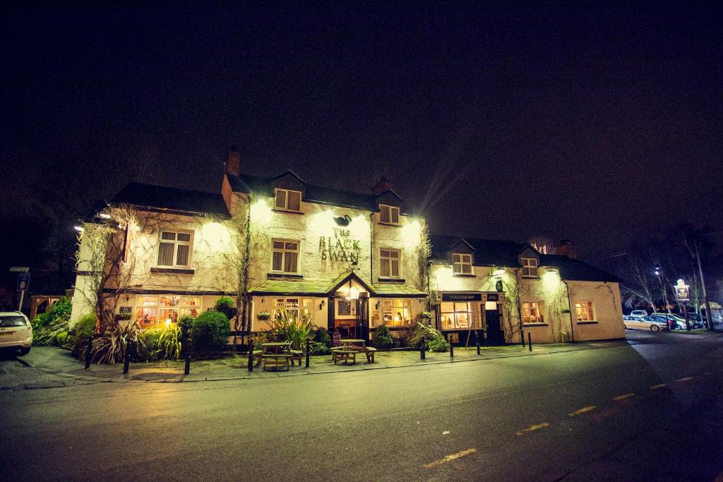 un edificio illuminato su una strada di notte di The Black Swan a Glazebrook