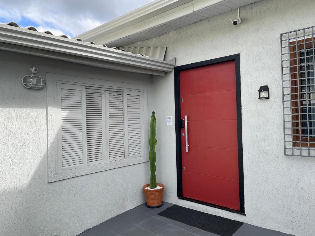 a red door of a house with a potted plant at Casa Completa com garagem in Curitiba
