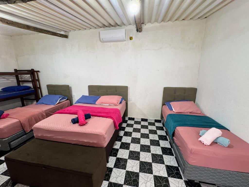 three beds in a room with a checkered floor at Suítes Ohana in Peruíbe