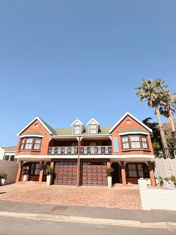 una gran casa de ladrillo con un árbol delante en Nimara de So, en Gordonʼs Bay