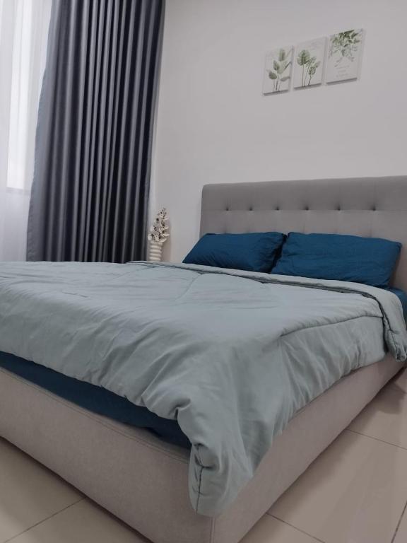 a bedroom with a large bed with blue pillows at Studio Unit Marc Residence in Bukit Mertajam