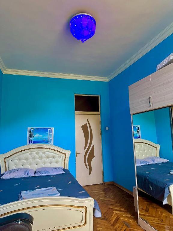 a blue bedroom with a bed and a mirror at KAR-SON family guesthouse & Tours in Yerevan
