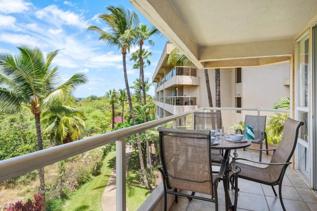a balcony with a table and chairs and palm trees at Maui Banyan P301 · MB P301 Remodeled 2BD Condo Across Beach Pool in Wailea