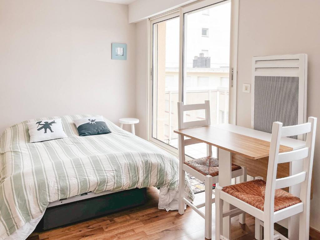 Un dormitorio con una cama y una mesa y una ventana. en Arthur, en Le Touquet-Paris-Plage