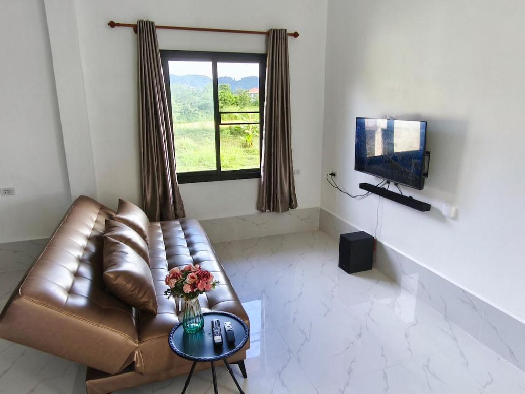 ein Wohnzimmer mit einem Ledersofa und einem TV in der Unterkunft Vang Vieng Cozy Villa in Vang Vieng