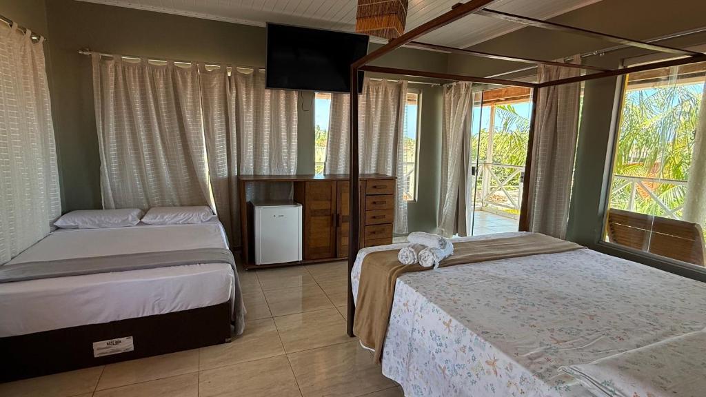 Un dormitorio con dos camas y una gran ventana. en Pousada O Portuga, en São Miguel dos Milagres