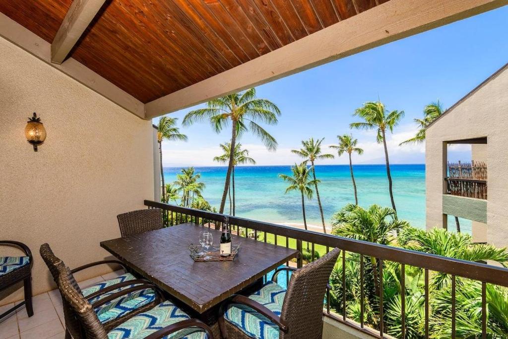 a balcony with a table and chairs and the ocean at Hale Mahina B401 · HM B401 OceanFront 2BD Tropical Getaway in Kahana