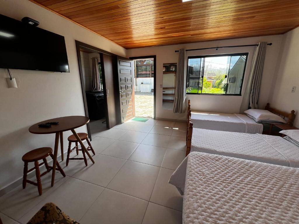 a room with two beds and a table and a tv at Pousada Jardim in Louro Müller
