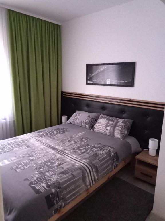 a bedroom with a bed with a green curtain at Giżycko Studio Apartament in Giżycko