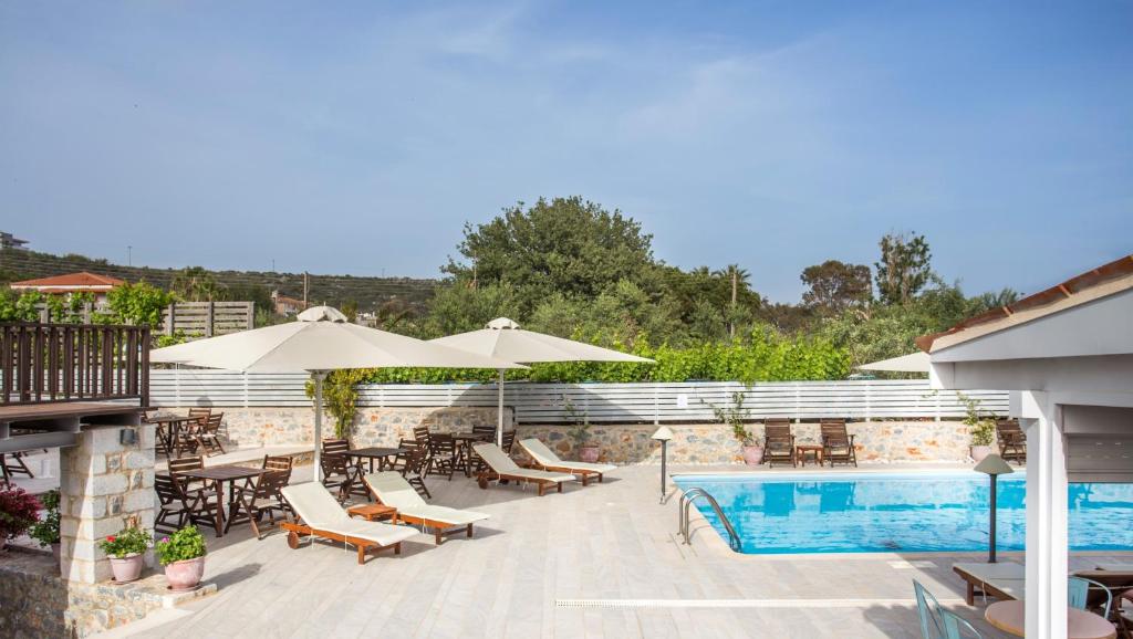 a swimming pool with chairs and umbrellas next to a building at Thirides Beach Resort in Gythio