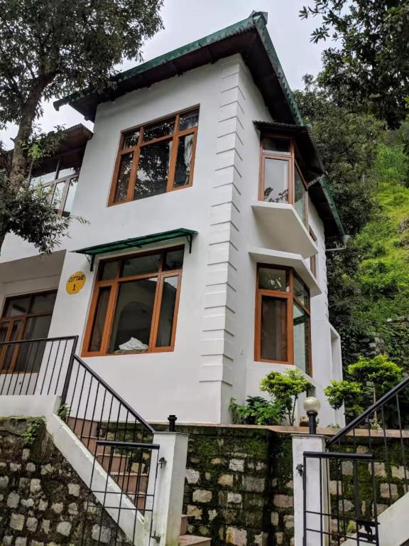 a white house with windows and stairs at HillNesst -Private 3-Bedroom Mountain Home in Bhowali in Bhowāli