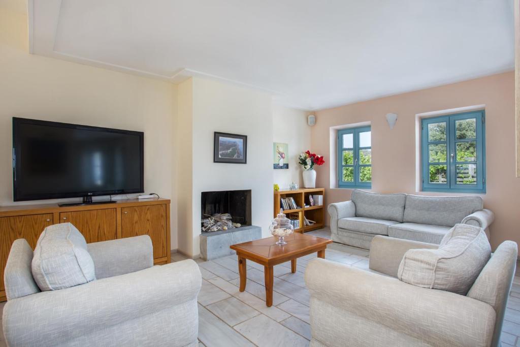a living room with two couches and a flat screen tv at Thirides Beach Resort in Gythio