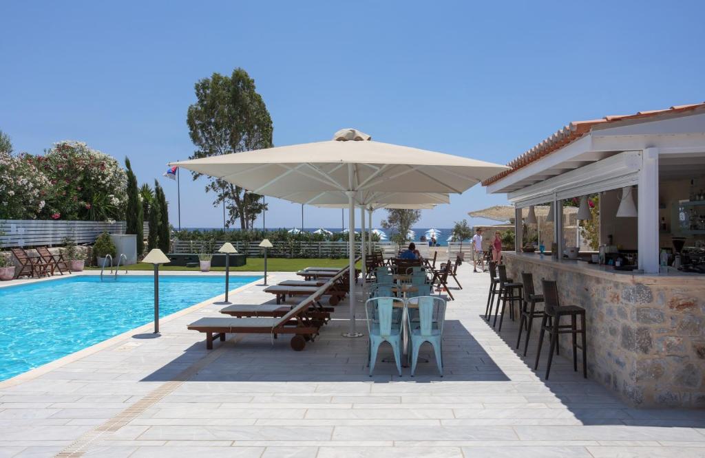 a patio with tables and umbrellas next to a pool at Thirides Beach Resort in Gythio