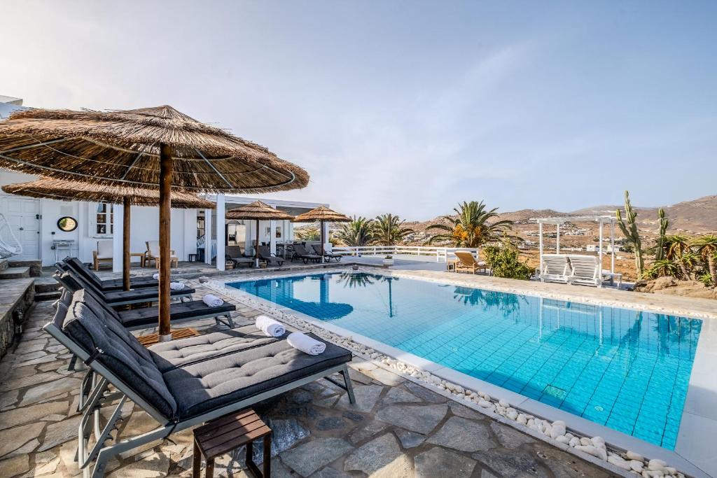 a pool with chaise lounge chairs and an umbrella at Manu Mykonos Exclusive Villa Luxury Beachside Stay with Private Pool by Quality Brand Villas in Kalafatis
