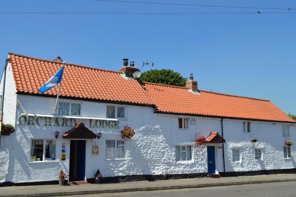 een wit gebouw met een rood dak bij Orchard Lodge & Wolds Restaurant in Scarborough