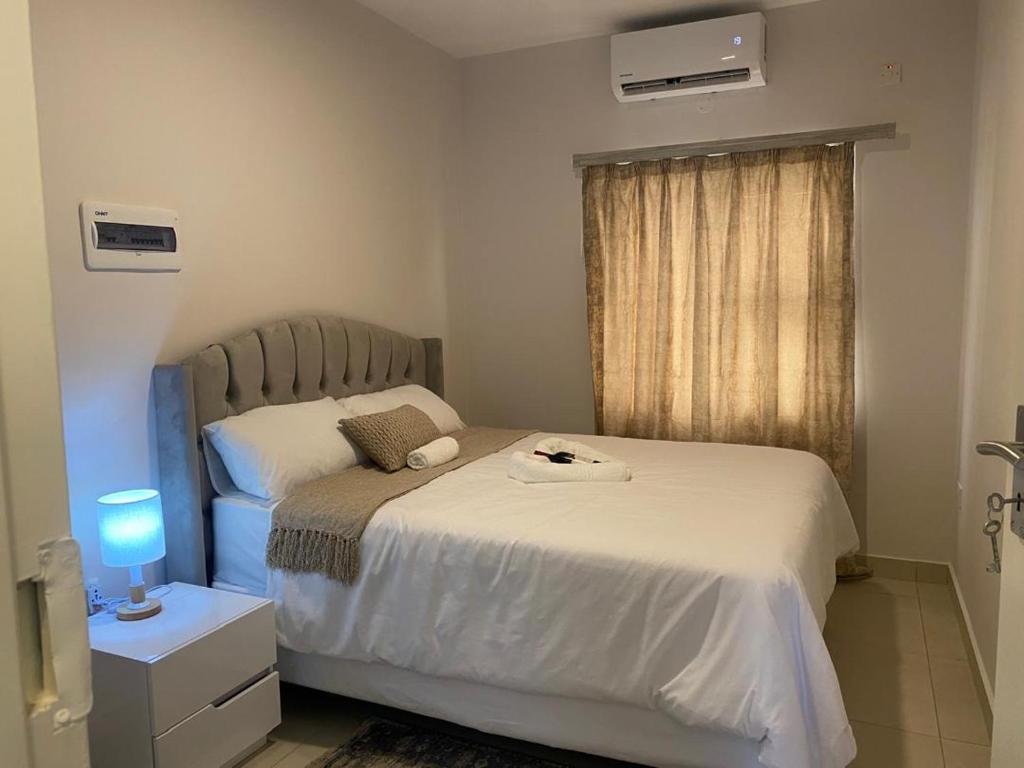 a small bedroom with a bed and a window at Kastina Suites at The Fig in Gaborone