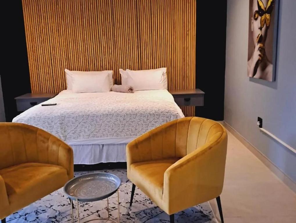 RandfonteinにあるGuesthouse in Randfonteinのベッドと椅子2脚のある寝室