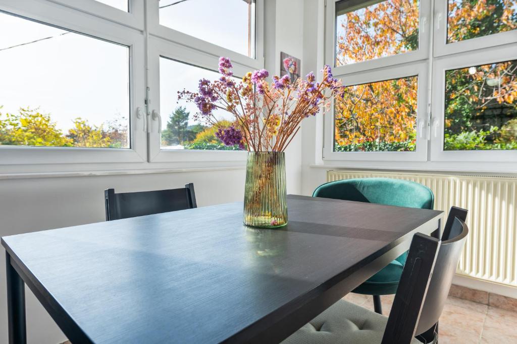 un vase de fleurs sur une table dans une chambre avec fenêtres dans l'établissement Hiša pod lipo - Apartma Lipa, à Slovenska Bistrica