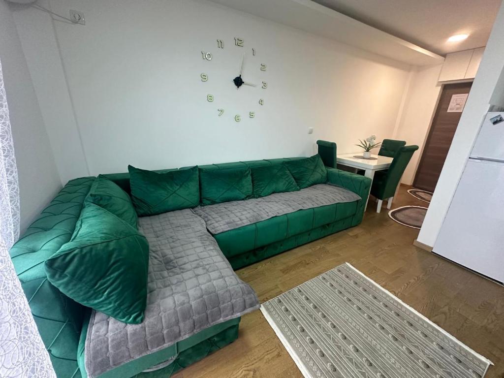 a green couch in a living room with a clock on the wall at Panorama in Bukorovac