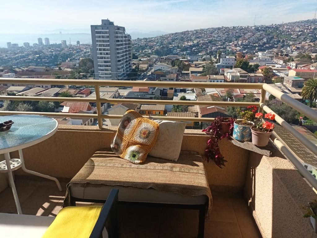 a bench on a balcony with a view of a city at Hospedaje en departamento compartido in Valparaíso