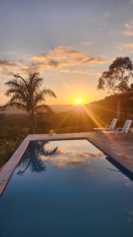 a swimming pool with a sunset in the background at Pousada Recanto e Aconchego Capitolio in Capitólio