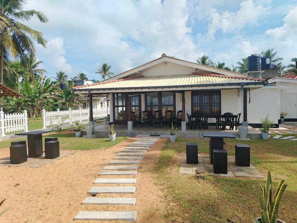 a house with picnic tables in front of it at Samudura Beach House, Owakanda in Rathgama