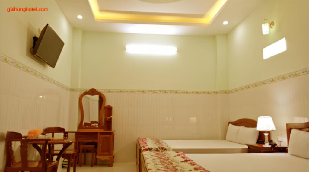 金瓯Khách sạn Gia Hưng的一间卧室配有一张床、一张桌子、一张床和电视。