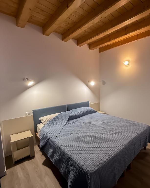 a bedroom with a blue bed in a room with wooden ceilings at B&B Battista in Sacile