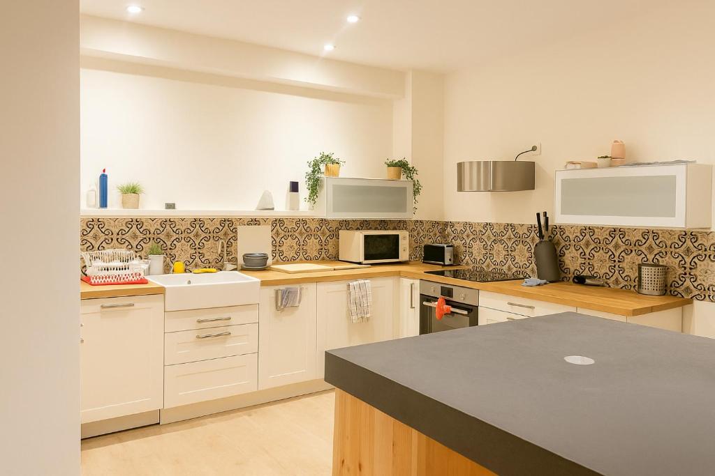 a kitchen with white cabinets and a black counter top at Le 9 Privé Chambres Chic à Puteaux près Paris, kitchen et 2 SDB ideal couples et Professionnels en déplacement in Puteaux