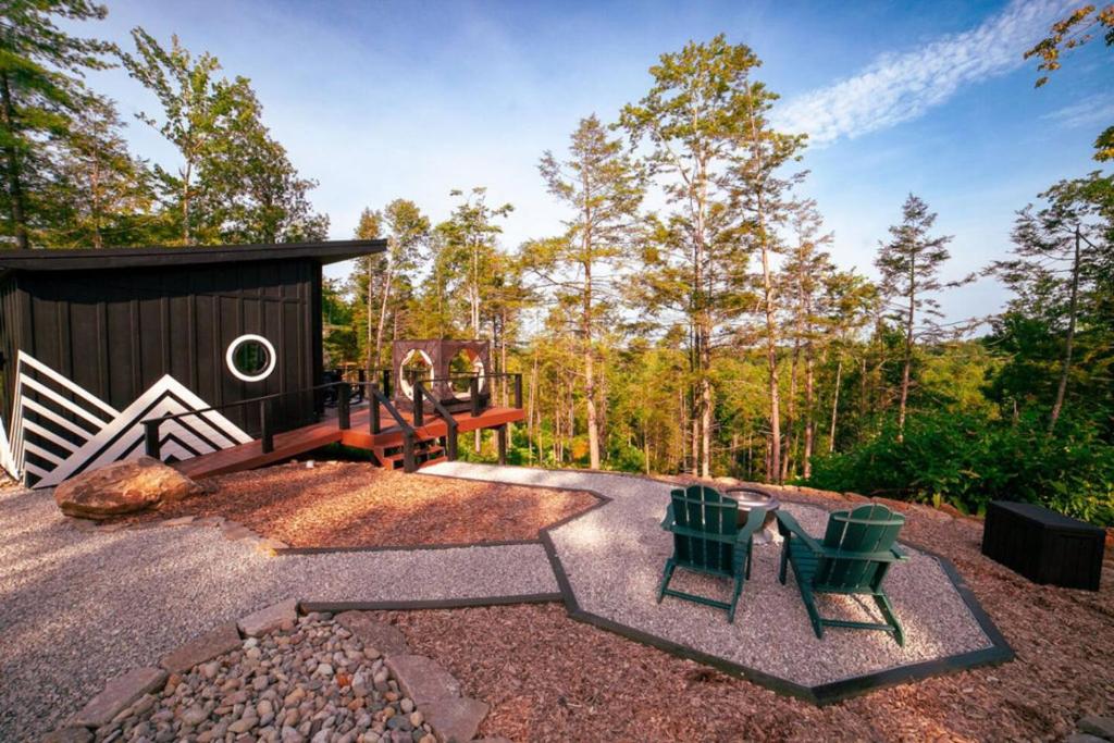 ein Hinterhof mit Spielplatz, Stühlen und einem Gebäude in der Unterkunft Private Lux Getaway Hot Tub Double Shower Cabana in Campton