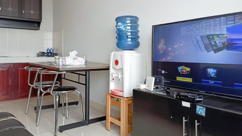 a kitchen with a tv and a table with a video game at COZY 2BR Pinewood Apt Jatinagor in Cilimus 2