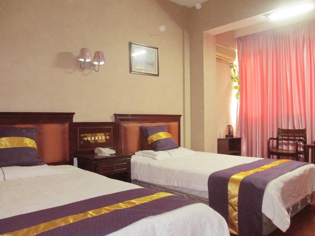 a hotel room with two beds and a window at Taizhou Taishan Business Hotel in Taizhou