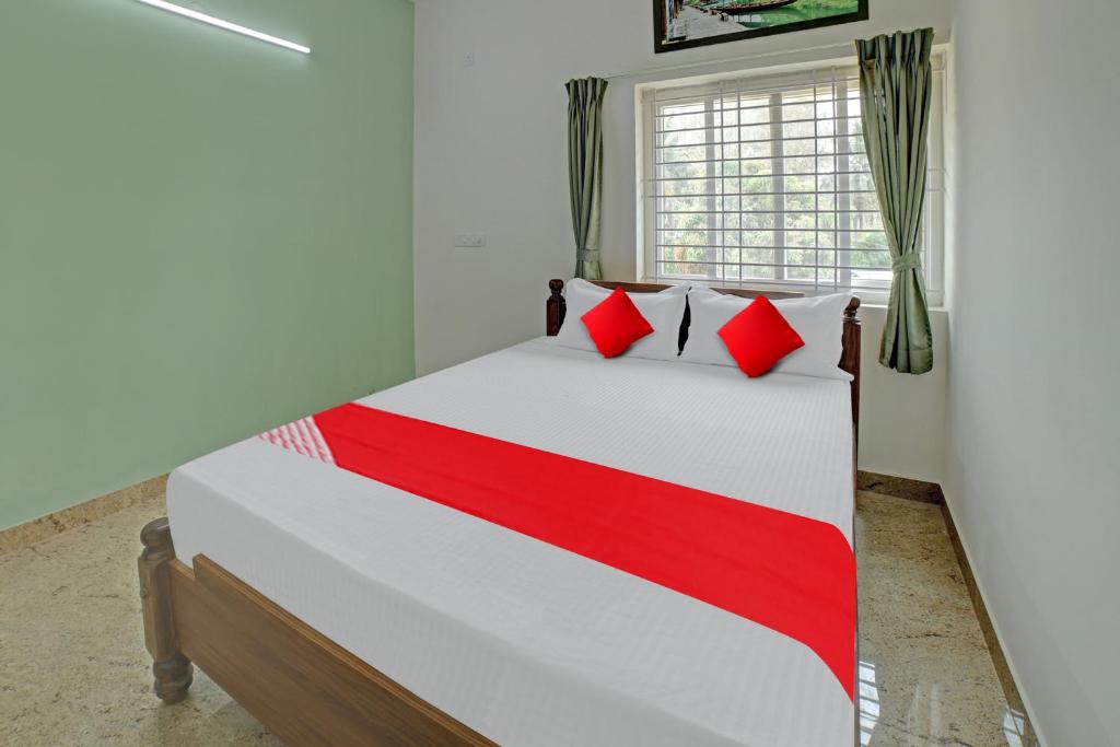a bedroom with a large bed with red pillows at Hotel O M & M Hospitality in Bengaluru