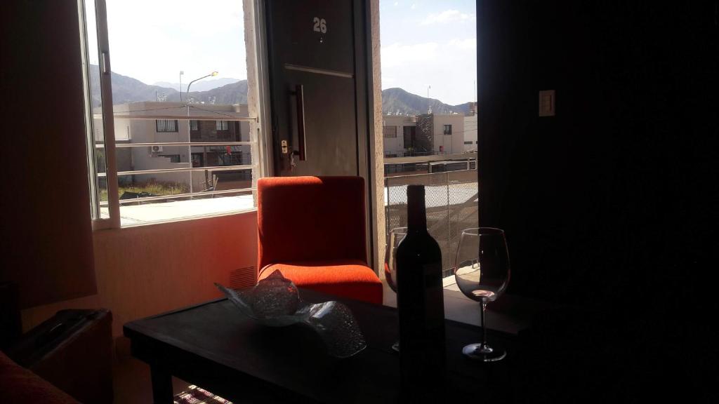 a window with a chair and a bottle and a wine glass at DEPARTAMENTOS BOUTIQUE DE DISEÑADOR " TERRAZA 26" - Cochera- Vista a la Montaña- CANCELACIÓN GRATUITA- PAGARÁS EN EL ALOJAMIENTO in Mendoza
