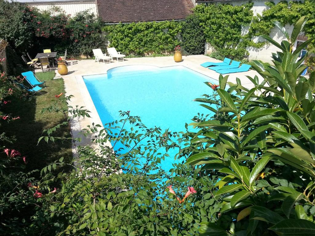 a swimming pool with blue chairs and plants at Tourterelle, à proximité de Auxerre et Chablis in Hauterive
