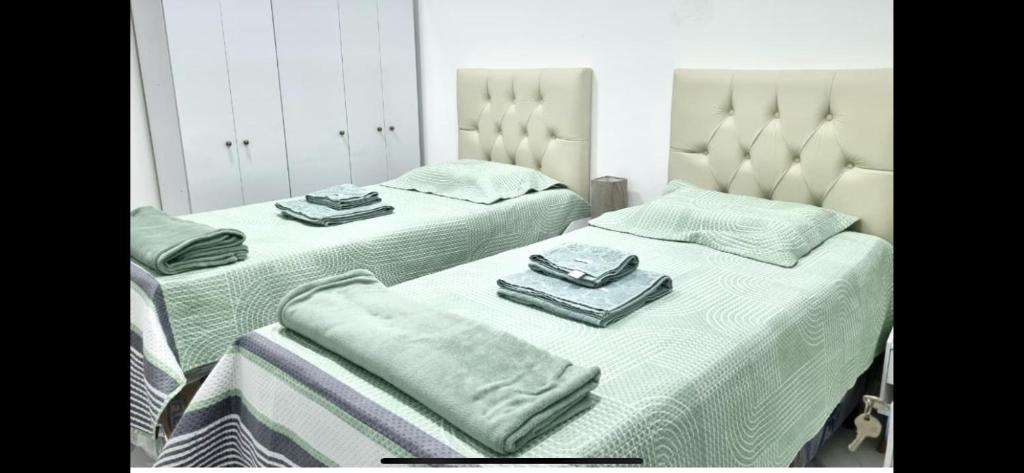 zwei Betten in einem Schlafzimmer mit Handtüchern darauf in der Unterkunft Casa aconchegante e bem localizada - São Brás in Belém