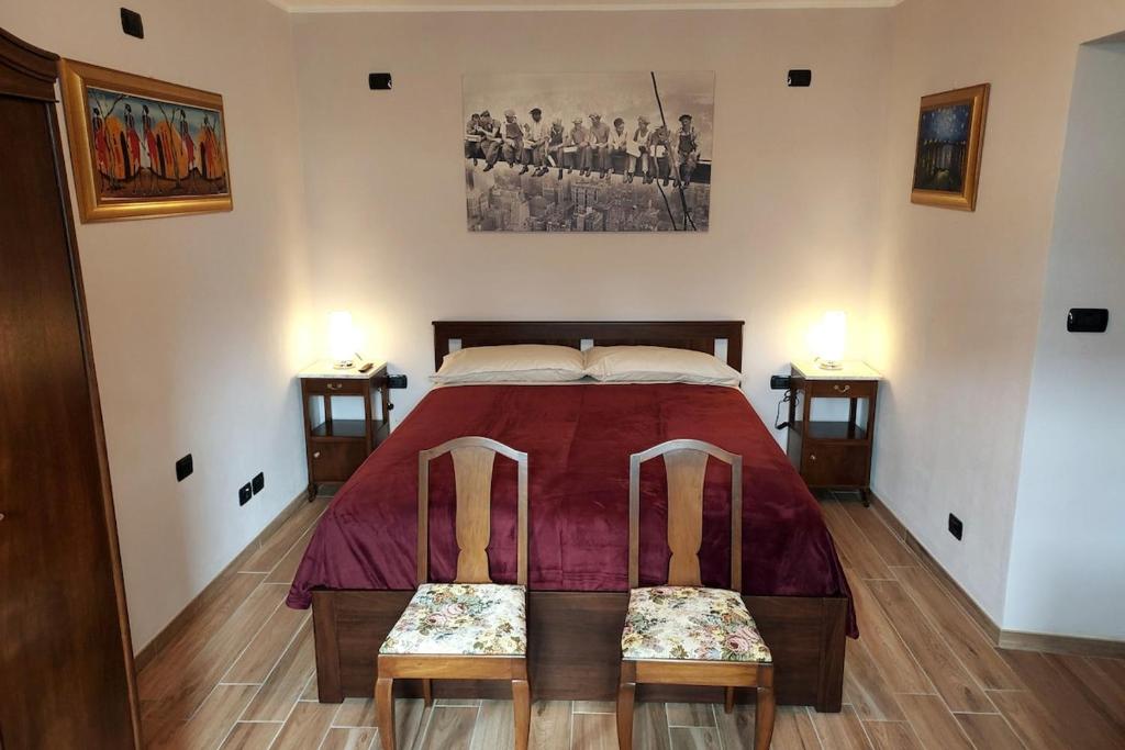 a bedroom with a large bed with two chairs at La Pergola in Postalesio