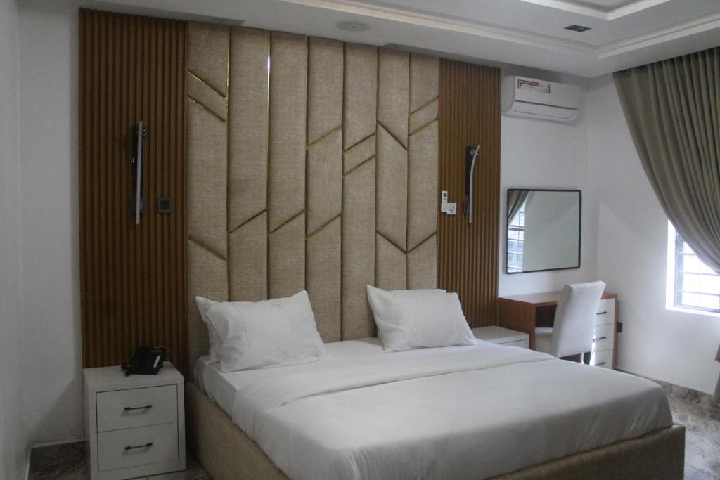 a bedroom with a large white bed and a desk at Grabbo Luxury Apartments in Gwarinpa