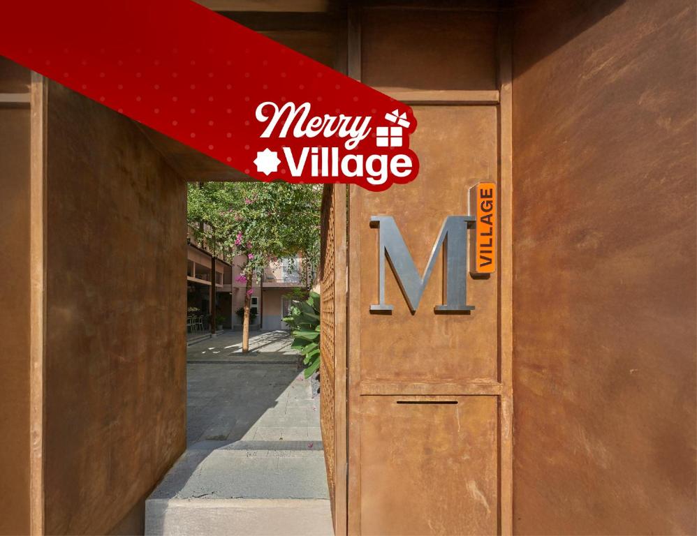 a sign on the door of a building with the words merry village at M Village Living Nam Kỳ Khởi Nghĩa in Ho Chi Minh City