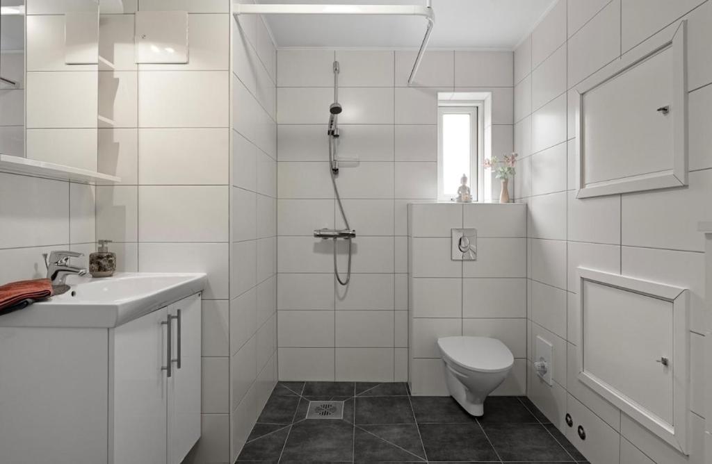 une salle de bain blanche avec douche et toilettes dans l'établissement Cozy apartment on tomasjordnes, à Tomasjorda