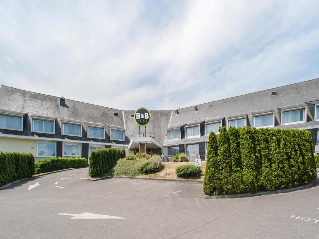 um parque de estacionamento vazio em frente a um edifício em B&B HOTEL Quimper Sud Bénodet em Quimper