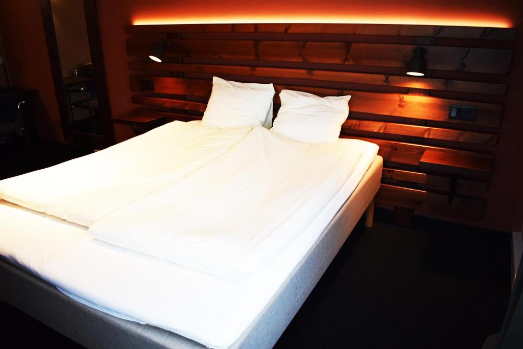 a large bed with white sheets and pillows at Åsele Wärdshus in Åsele