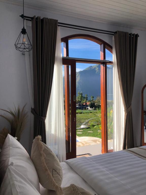 a bedroom with a bed and a large window at Skyland Kintamani in Kubupenlokan